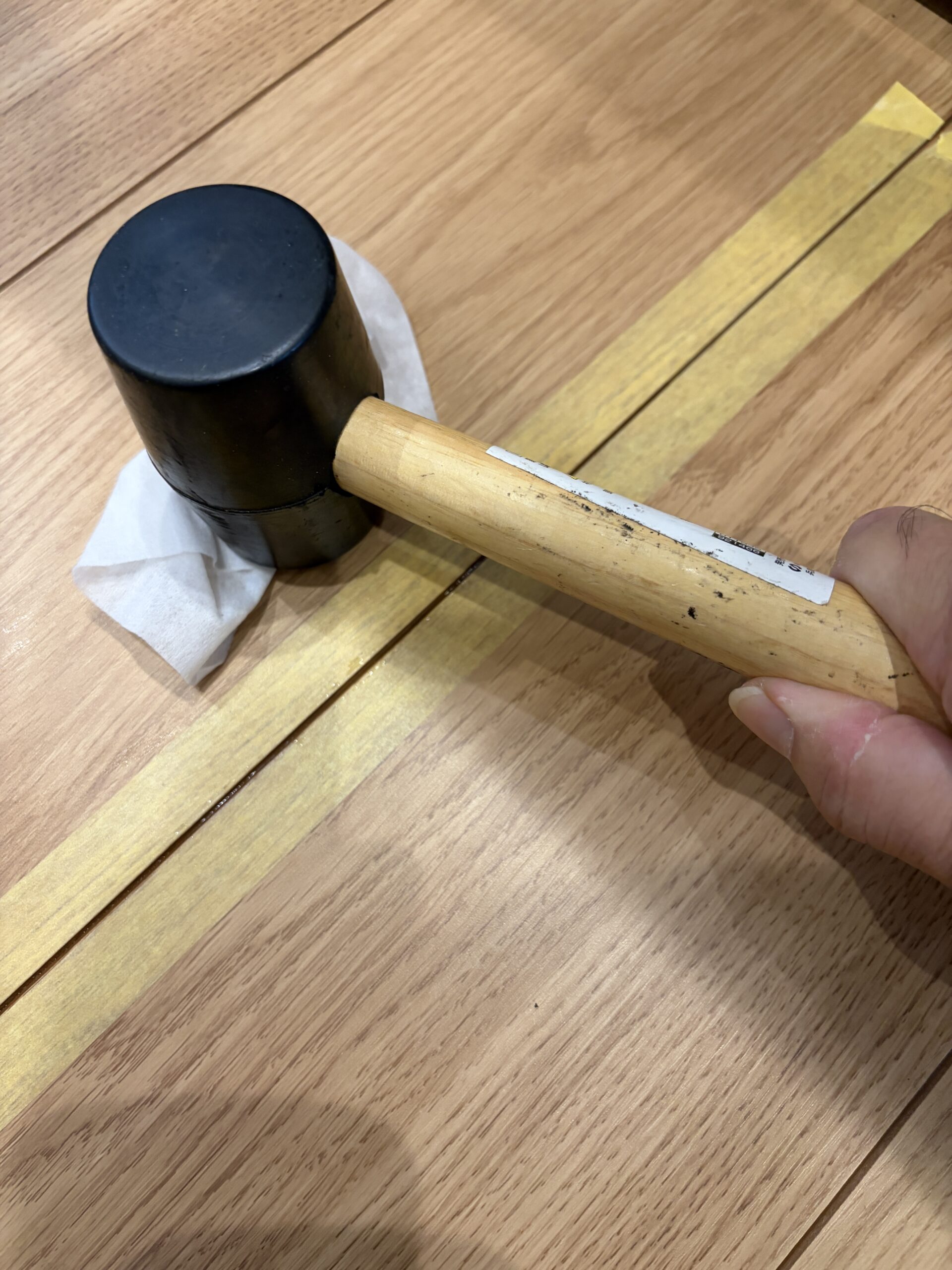 ゴムハンマーで目地周辺を叩いて振動させている様子